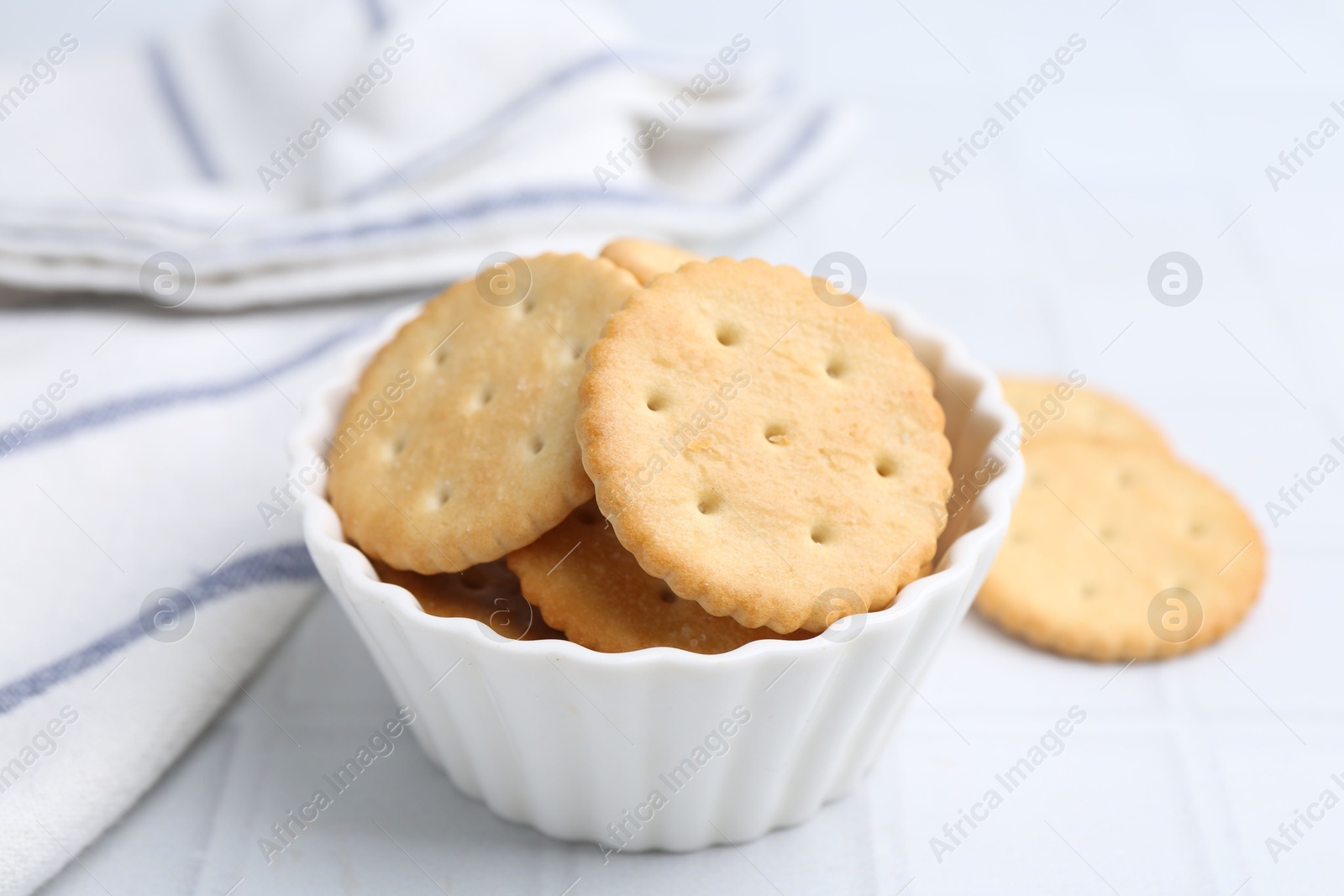 Tasty salty crackers on white tiled table, closeup Photo of Tasty salty crackers on white tiled table, closeup