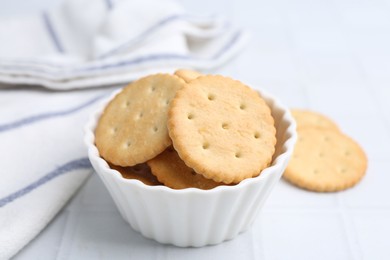 Photo of Tasty salty crackers on white tiled table, closeup