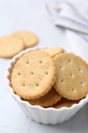 Photo of Tasty salty crackers on white tiled table, closeup