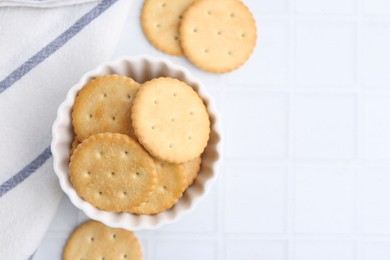 Photo of Tasty salty crackers on white tiled table, flat lay. Space for text
