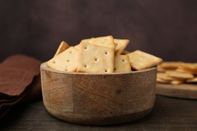 Photo of Tasty salty crackers on wooden table, closeup