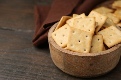 Photo of Tasty salty crackers on wooden table, closeup. Space for text