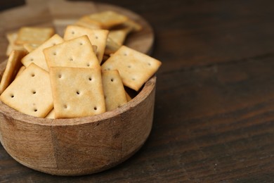 Photo of Tasty salty crackers on wooden table, closeup. Space for text