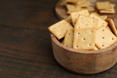 Photo of Tasty salty crackers on wooden table, closeup. Space for text