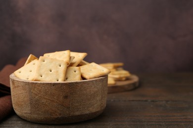 Photo of Tasty salty crackers on wooden table. Space for text