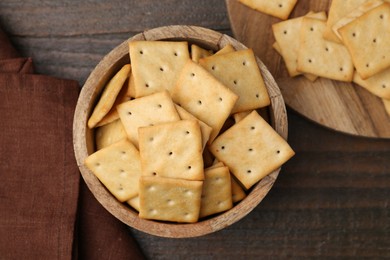 Photo of Tasty salty crackers on wooden table, top view