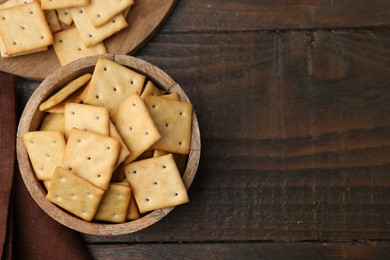 Photo of Tasty salty crackers on wooden table, top view. Space for text