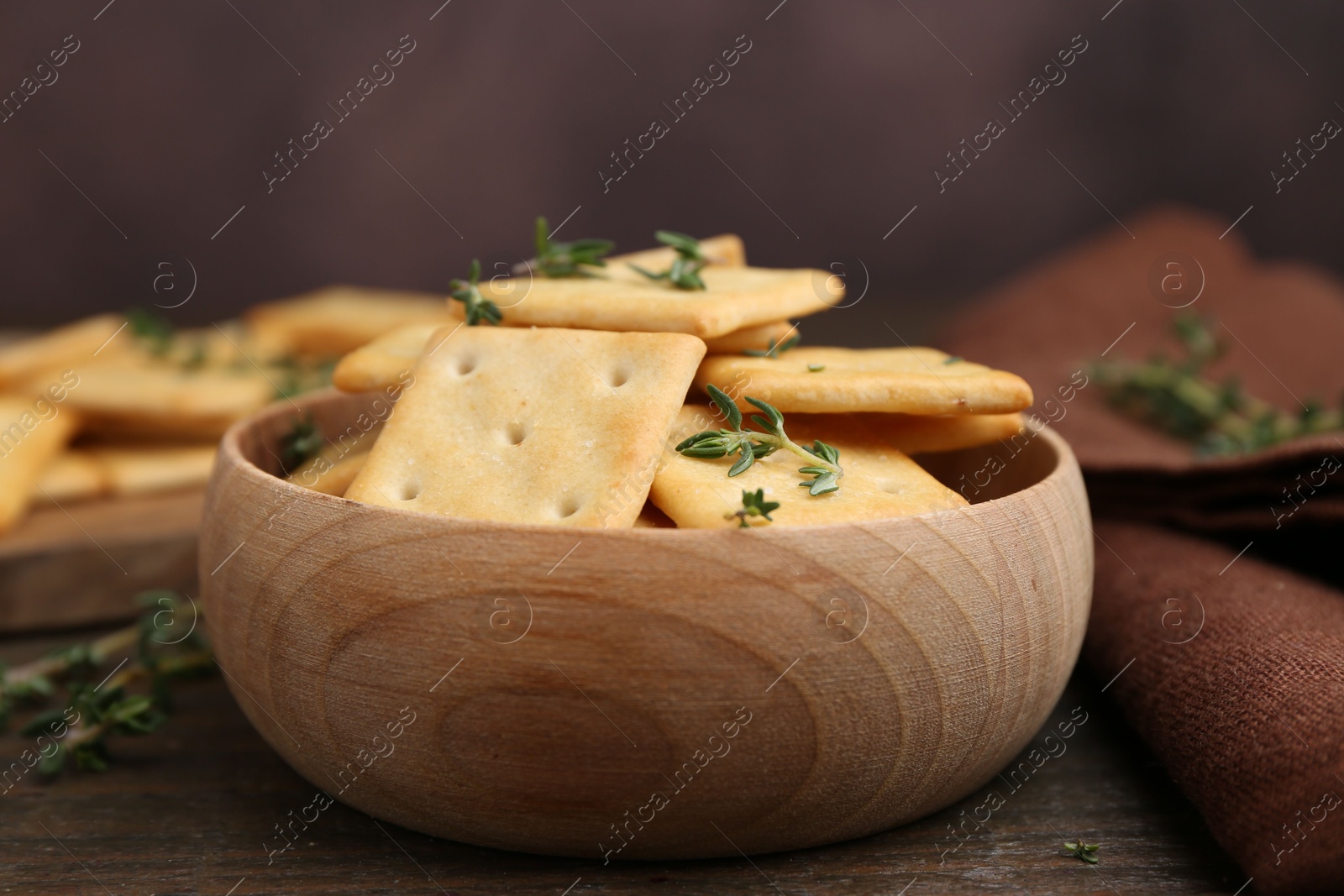 Tasty salty crackers with thyme on wooden table, closeup Photo of Tasty salty crackers with thyme on wooden table, closeup