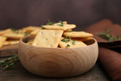 Photo of Tasty salty crackers with thyme on wooden table, closeup