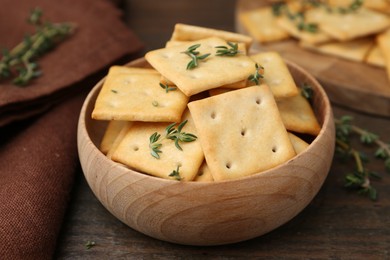 Photo of Tasty salty crackers with thyme on wooden table, closeup