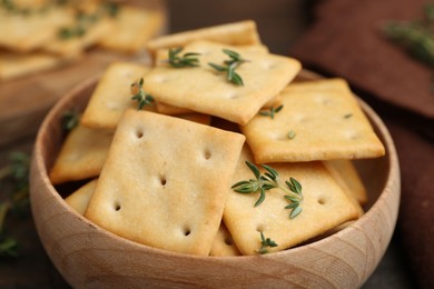 Photo of Tasty salty crackers with thyme on wooden table, closeup