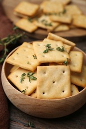 Photo of Tasty salty crackers with thyme on wooden table, closeup