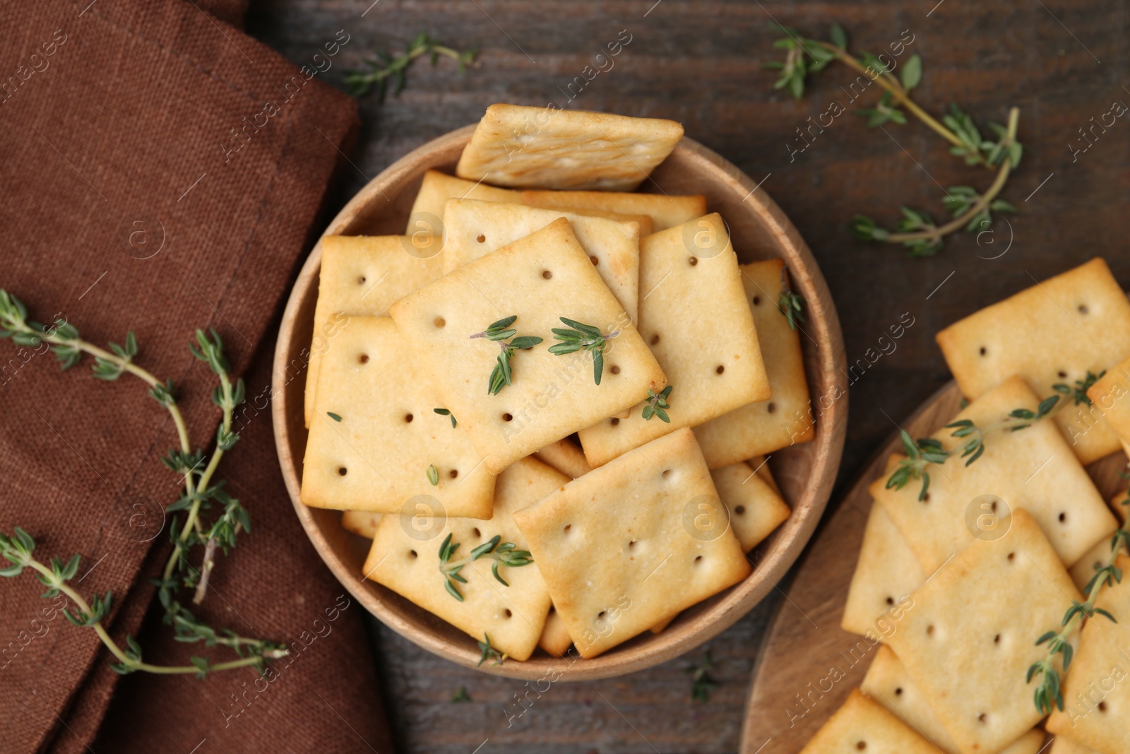 Tasty salty crackers with thyme on wooden table, flat lay Photo of Tasty salty crackers with thyme on wooden table, flat lay