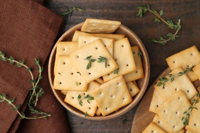 Photo of Tasty salty crackers with thyme on wooden table, flat lay