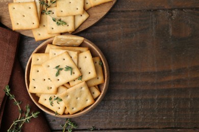 Photo of Tasty salty crackers with thyme on wooden table, flat lay. Space for text