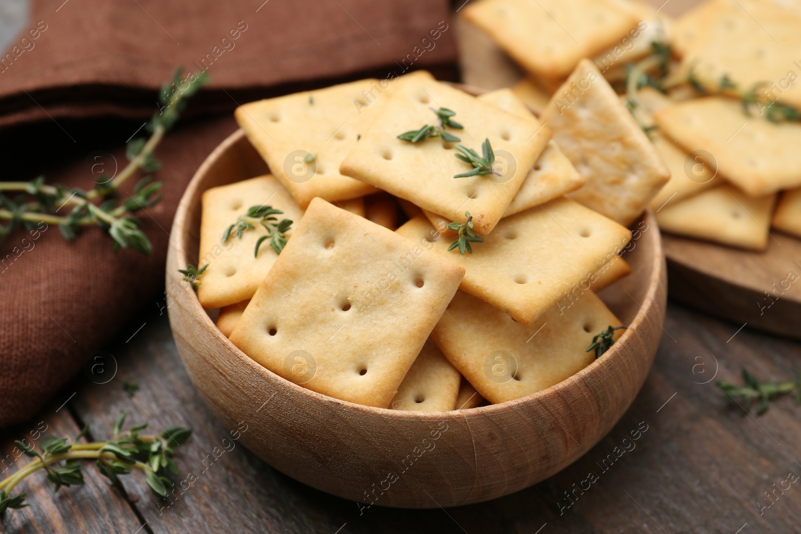 Tasty salty crackers with thyme on wooden table, closeup Photo of Tasty salty crackers with thyme on wooden table, closeup