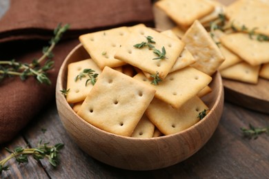 Photo of Tasty salty crackers with thyme on wooden table, closeup