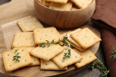 Photo of Tasty salty crackers with thyme on wooden table, closeup