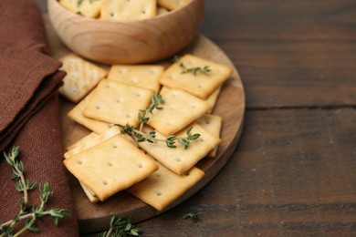Photo of Tasty salty crackers with thyme on wooden table, closeup