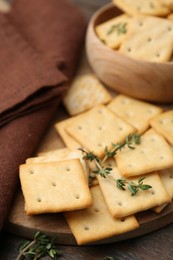 Photo of Tasty salty crackers with thyme on wooden table, closeup