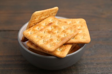 Photo of Tasty salty crackers on wooden table, closeup