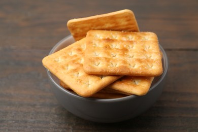 Photo of Tasty salty crackers on wooden table, closeup