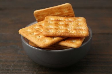 Photo of Tasty salty crackers on wooden table, closeup