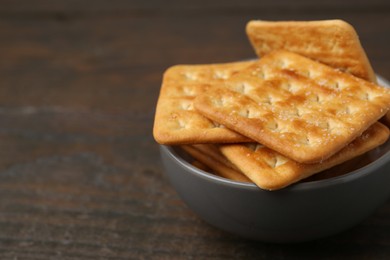 Photo of Tasty salty crackers on wooden table, closeup. Space for text
