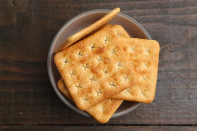 Photo of Tasty salty crackers on wooden table, top view
