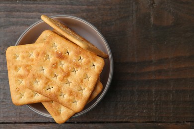 Photo of Tasty salty crackers on wooden table, top view. Space for text