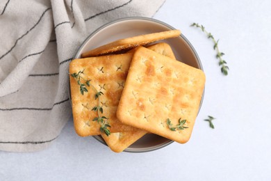 Photo of Tasty salty crackers with thyme on white table, top view