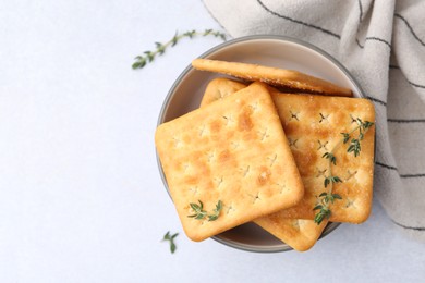 Photo of Tasty salty crackers with thyme on white table, top view. Space for text
