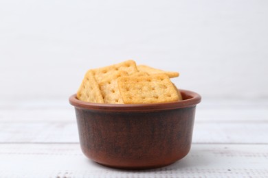 Photo of Tasty salty crackers on white wooden table, closeup