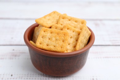 Photo of Tasty salty crackers on white wooden table, closeup