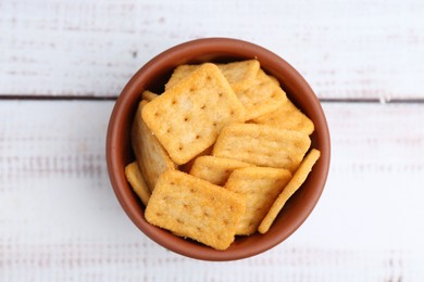 Photo of Tasty salty crackers on white wooden table, top view