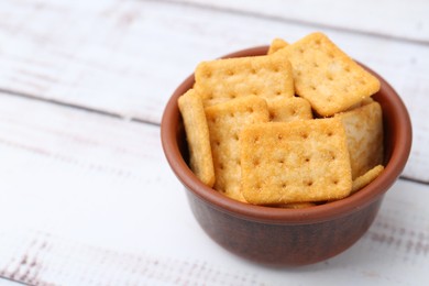 Photo of Tasty salty crackers on white wooden table, closeup. Space for text