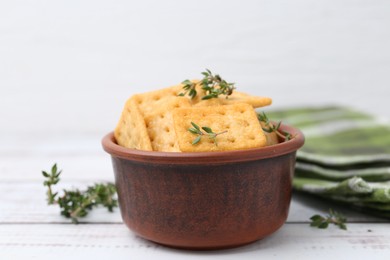 Photo of Tasty salty crackers with thyme on white wooden table, closeup