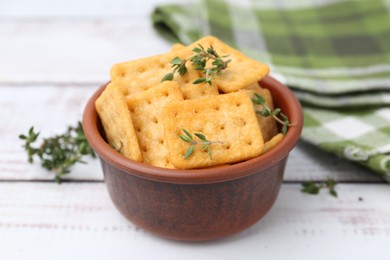 Photo of Tasty salty crackers with thyme on white wooden table, closeup