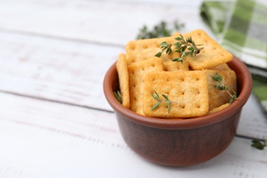Photo of Tasty salty crackers with thyme on white wooden table, closeup. Space for text