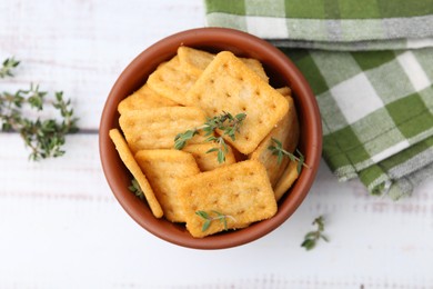 Photo of Tasty salty crackers with thyme on white wooden table, flat lay