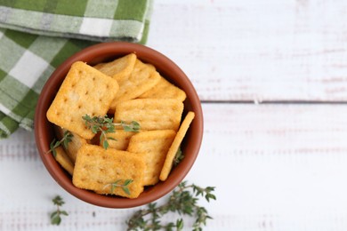 Photo of Tasty salty crackers with thyme on white wooden table, flat lay. Space for text