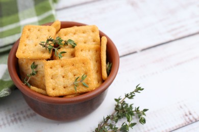 Photo of Tasty salty crackers with thyme on white wooden table, closeup. Space for text