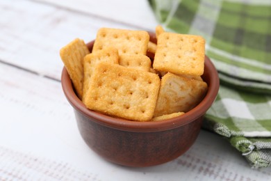Photo of Tasty salty crackers on white wooden table, closeup