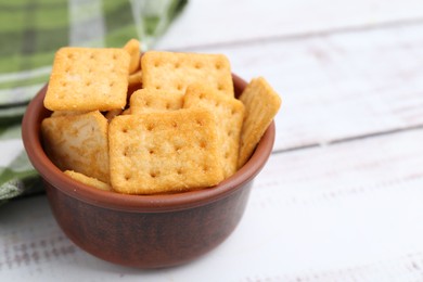 Photo of Tasty salty crackers on white wooden table, closeup