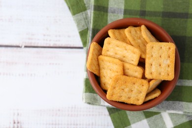 Photo of Tasty salty crackers on white wooden table, top view. Space for text