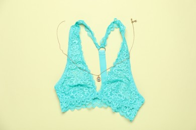 Photo of Beautiful lace bra and pendant on light green background, flat lay