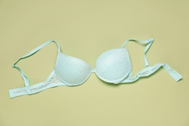 Photo of Beautiful lace bra on light green background, top view