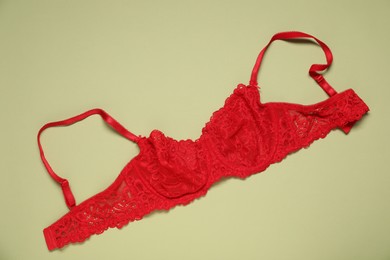 Photo of Beautiful red lace bra on light green background, top view