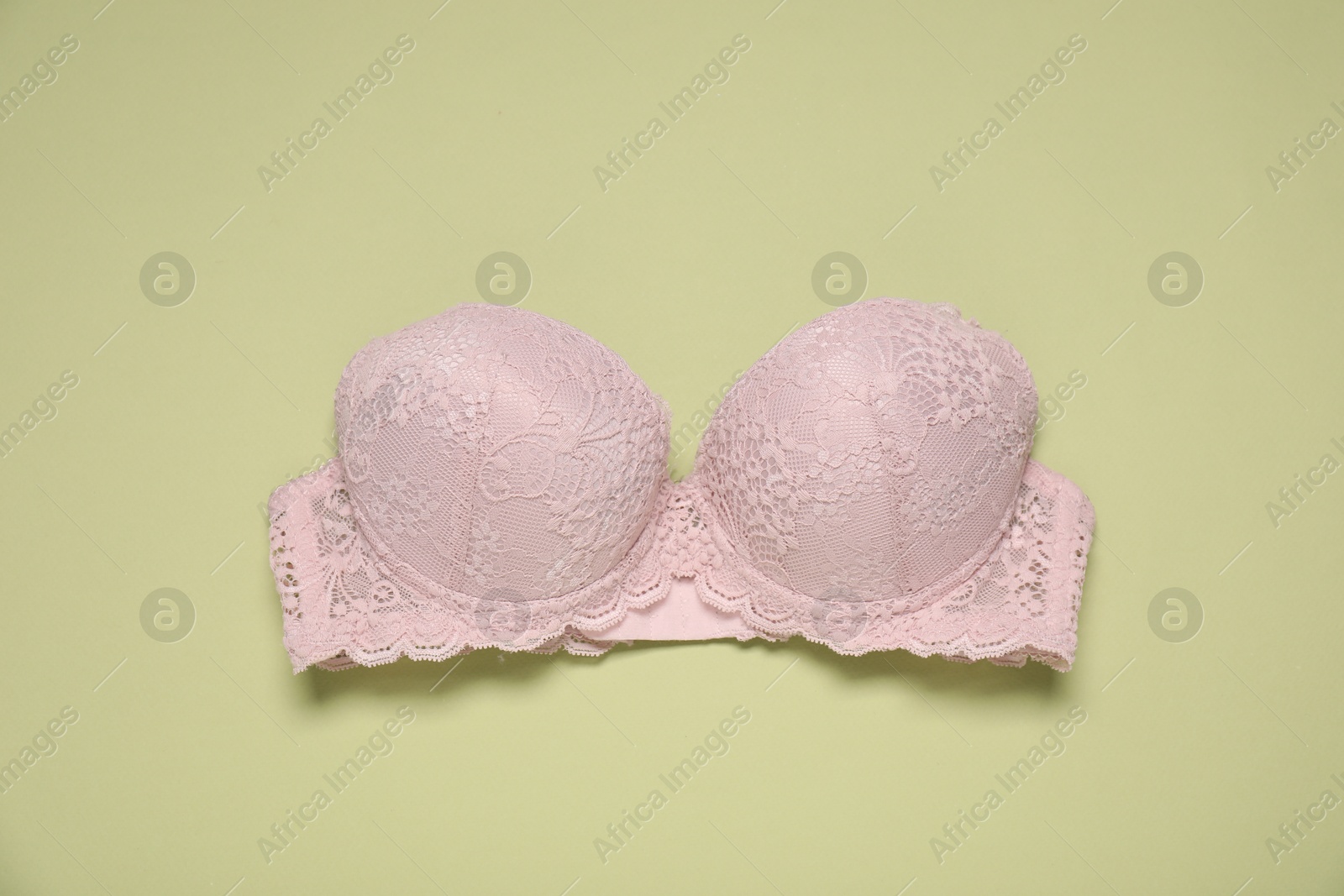 Beautiful beige lace bra on light green background, top view Photo of Beautiful beige lace bra on light green background, top view