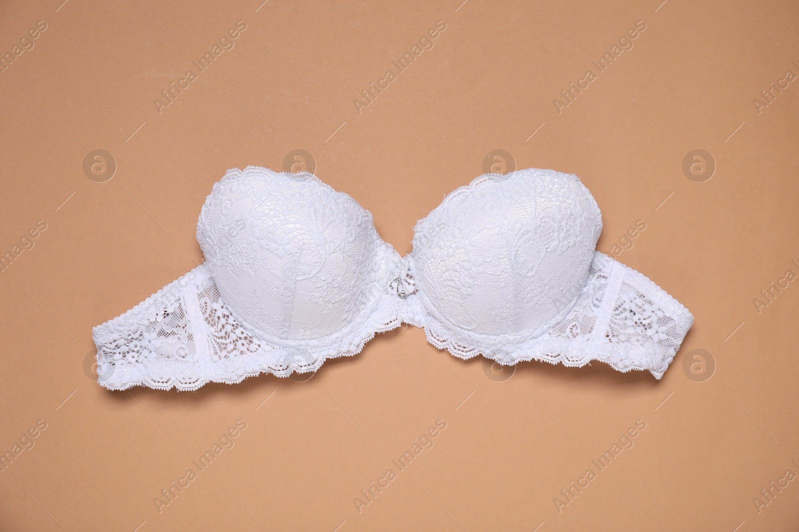 Beautiful white lace bra on beige background, top view Photo of Beautiful white lace bra on beige background, top view